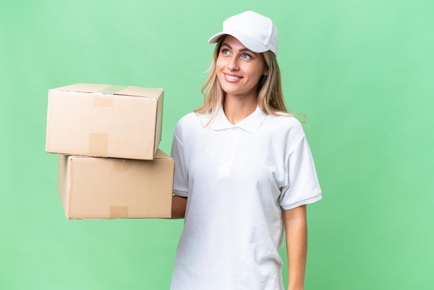 Delivery Uruguayan woman over isolated background thinking an idea while looking up