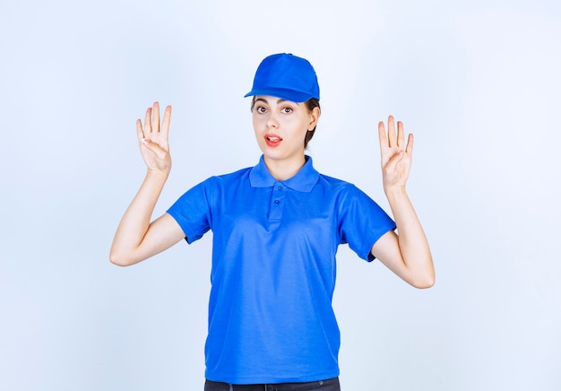 Delivery woman employee in blue uniform standing and looking at camera .