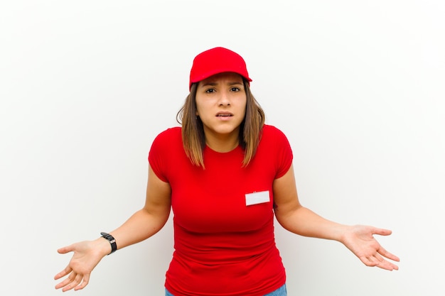 Delivery woman feeling clueless and confused, having no idea, absolutely puzzled with a dumb or foolish look against white background