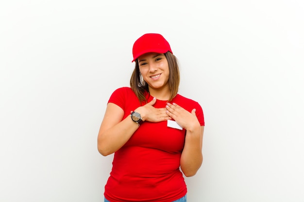 Donna di consegna sentirsi romantica, felice e innamorata, sorridendo allegramente e tenendosi per mano vicino al cuore contro il bianco