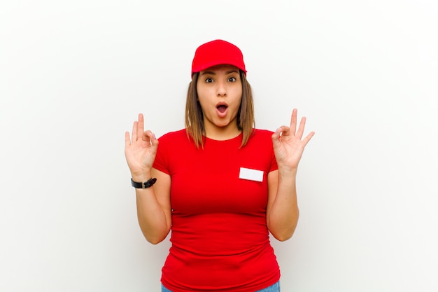 Delivery woman feeling shocked, amazed and surprised, showing approval making okay sign with both hands