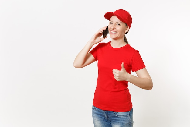 Donna di consegna in uniforme rossa isolata su fondo bianco. donna in berretto, t-shirt, jeans che lavora come corriere o rivenditore parlando al cellulare, parlando, conversando. copia spazio per la pubblicità.