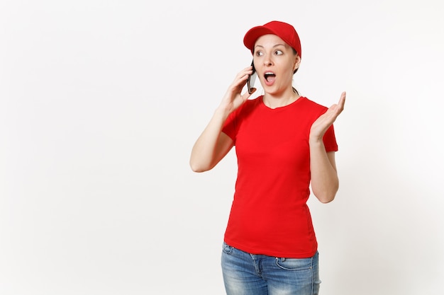 Женщина-доставщик в красной форме, изолированные на белом фоне. Женщина в кепке, футболке, джинсах работает курьером или дилером, разговаривает по мобильному телефону, разговаривает, разговаривает. Скопируйте место для рекламы.
