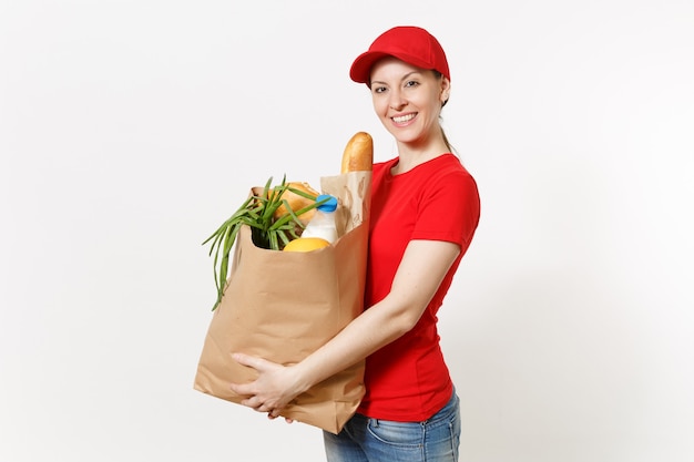 Donna di consegna in uniforme rossa isolata su fondo bianco. corriere femminile in berretto, t-shirt, jeans che tengono il pacchetto di carta con il cibo. consegna prodotti da negozio o ristorante a casa tua. copia spazio.