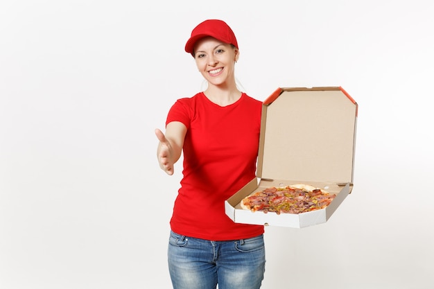 Delivery woman in red uniform isolated on white background. Pretty female in cap, t-shirt, jeans working as courier or dealer holding italian pizza in cardboard flatbox. Copy space for advertisement