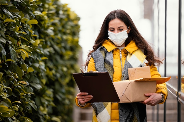 Donna di consegna con maschera che trasporta pacchetto