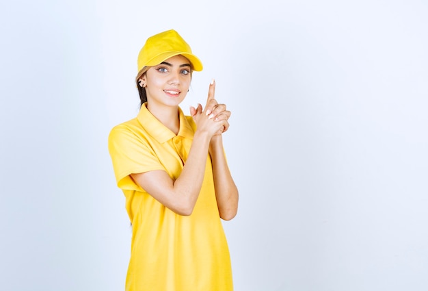 Delivery woman in yellow uniform holding fingers up like a pistol.