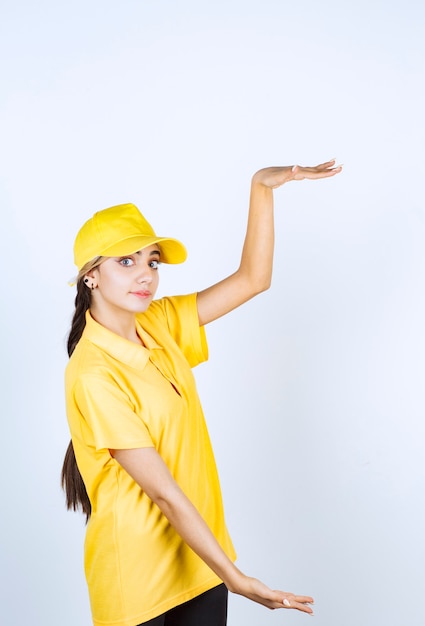 Delivery woman in yellow uniform standing and showing size with hands.