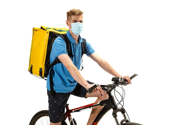 Deliveryman in face mask with bicycle isolated on white studio background. Contacless service during quarantine. Man delivers food during isolation. Safety. Professional occupation. Copyspace for ad.