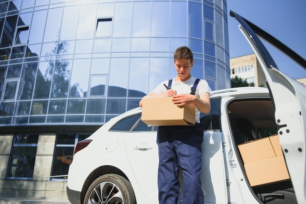 Photo deliveryman holds parcels at the car, delivering