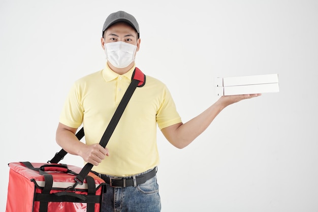 Deliveryman with big insulated bag wearing medical mask when delivering pizza