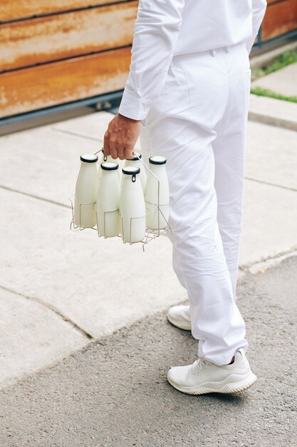 Delvery man carrying glass bottles to entrance of customer