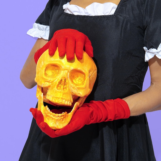 Demonic gothic stylish Lady in red gloves holding gold skull