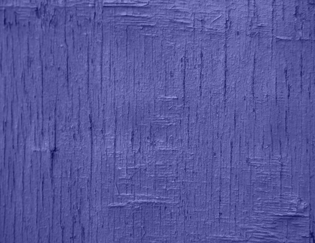 Demonstrating the fashionable color of 2022 - purple. A background of purple, peeling paint on an old wooden wall.