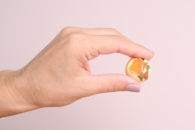 Demonstration of chocolate candie with nut or fruit filling on the outstretched fingers of a female hand