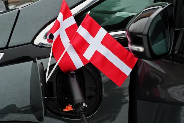 Denemarken vlag ecologische auto concept. Een stroomleverancier aansluiten, moderne auto opladen.