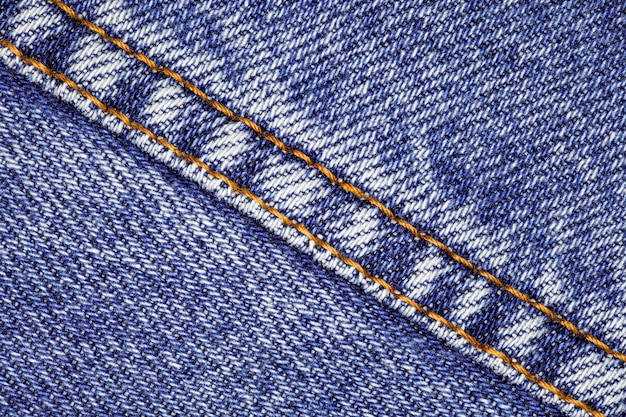 Denim dark blue and suture sewn with orange threads closeup background wallpaper uniform texture pattern