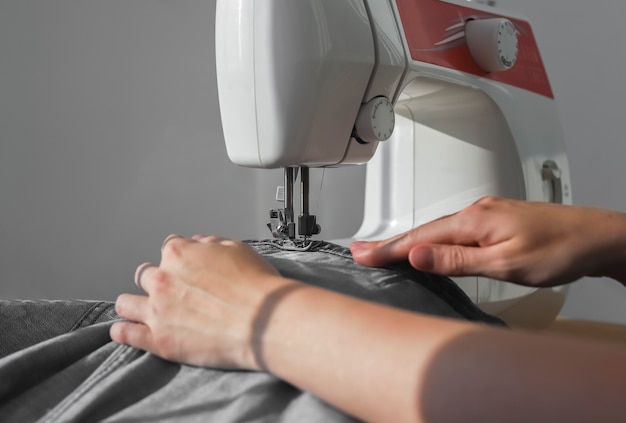 Denim fabric on sewing machine close up needlewoman hands at manual work