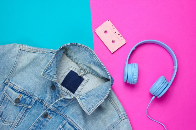 青ピンクの背景にデニムジャケット、ヘッドフォン、オーディオカセット