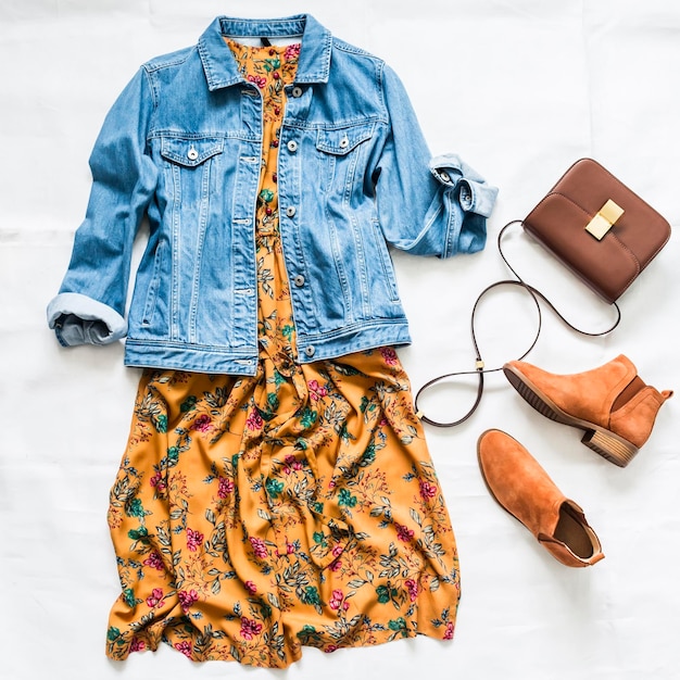 Denim jacket vintage floral print dress suede red chelsea boots\
and leather bag on a light background top view beauty fashion\
concept