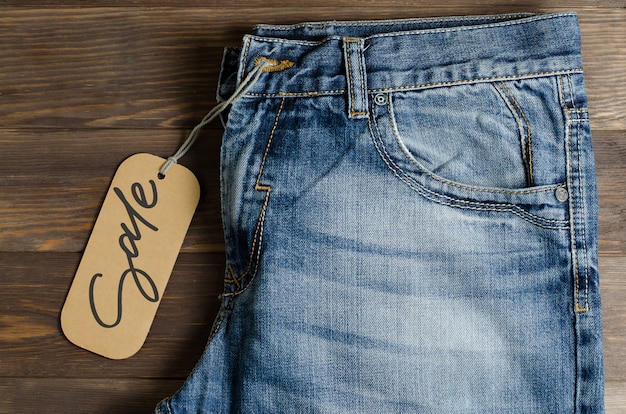 Denim. Jeans op bruine houten. Verkoop, handgeschreven inscriptie op een papieren etiket.