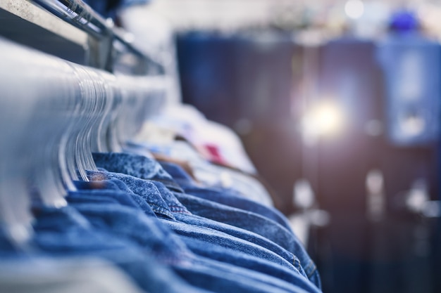 Denimoverhemden hangen aan hangers op een rij. Kledingwinkel. Stijl