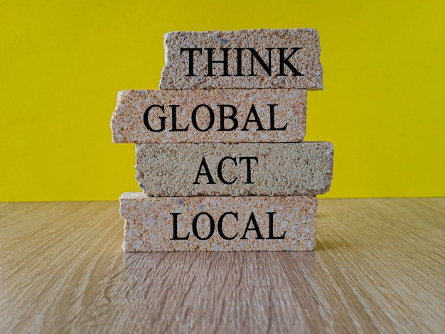 Denk aan global act local symbol Baksteenblokken vormen de woorden