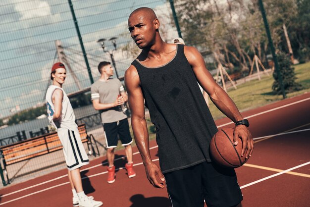 Denken aan succes. Jonge Afrikaanse man in sportkleding die wegkijkt terwijl hij buiten basketbal speelt