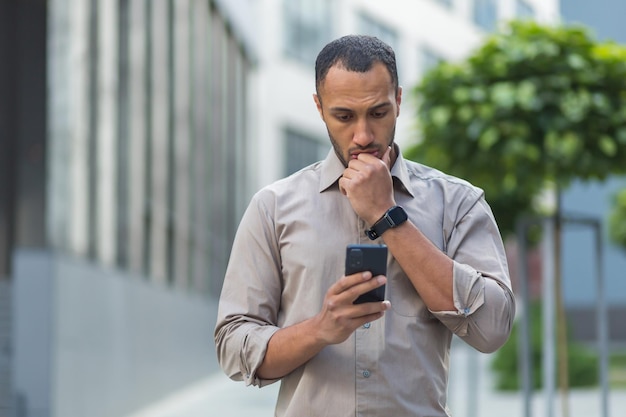 Denkende en verdrietige moslimzakenman die bericht leest van smartphoneman buiten kantoorgebouw