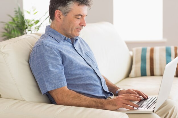 Denkende mensenzitting op bank die laptop met behulp van