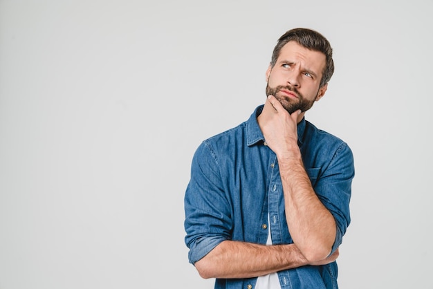 Denkende nadenkende overwegende blanke jonge man die nadenkt over toekomstige plannen nieuwe start-up die naar boven kijkt geïsoleerd op witte achtergrond