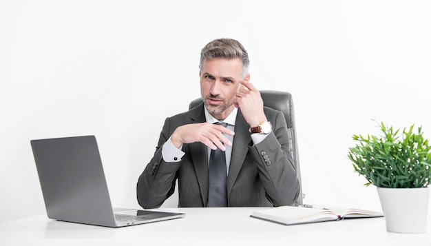 Denkende zakenman zit in een kantoor met een laptop.