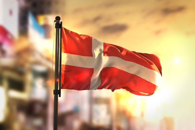 Photo denmark flag against city blurred background at sunrise backlight