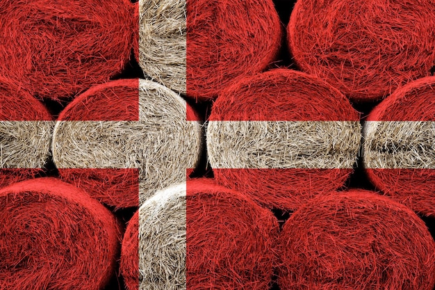 Denmark flag on the surface of a stack of hay rolls