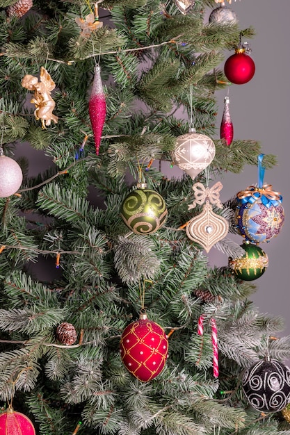 Dennenboom versierd voor kerstmis of nieuwjaarsviering met neutrale grijze achtergrond.