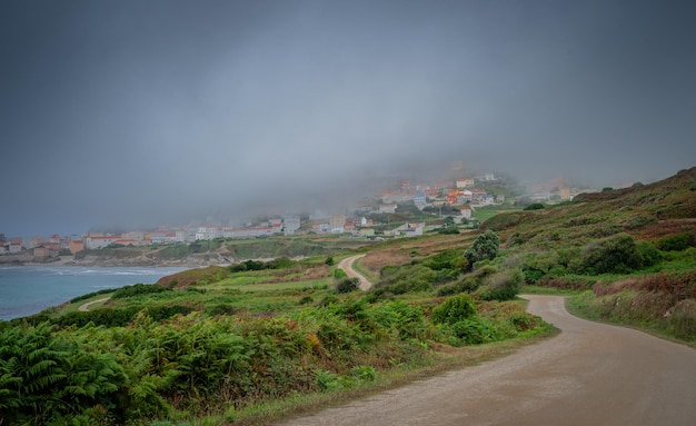 A dense dark fog covers part of a coastal village