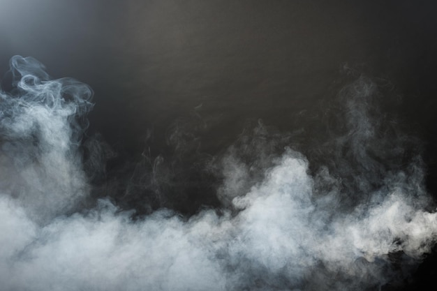 Фото Плотные пушистые клубы белого дыма и тумана на черном фоне, абстрактные облака дыма, размытое движение не в фокусе. дымящие удары от машинной мухи с сухим льдом и развевающиеся в воздухе, эффект текстуры