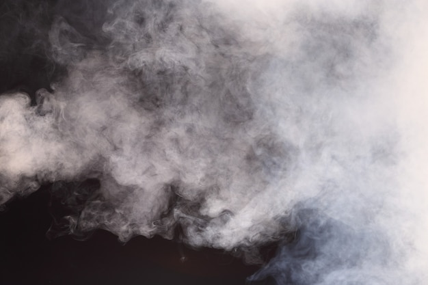 Dense fluffy puffs of white smoke and fog on black background, abstract smoke clouds, all movement blurred, intention out of focus, and high low exposure contrast, copy space for text logo