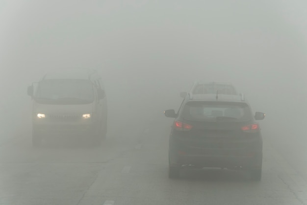 Dense fog and poor visibility on the road. Dangerous driving situations. View on highway traffic. Misty morning. Low visibility. Smoke on the road. cars driving trough mist. emergency danger on road.