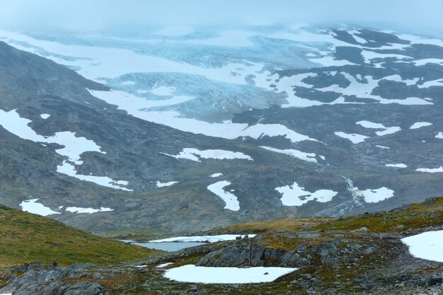 Photo dense fog and summer mountain landscape with lake and snow (norway, not far nigardsbreen glacier).