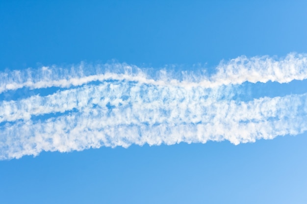 Dense puffs of white smoke left by flying planes, chemical trails.