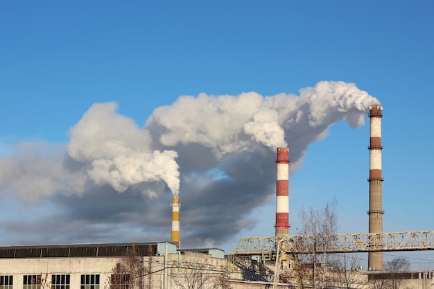 Dense smoke burst from the three factory chimneys.