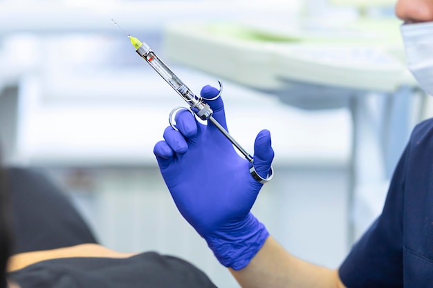 Photo dental anesthesia syringe in hand of dentist. doctor doing anesthesia to patient.