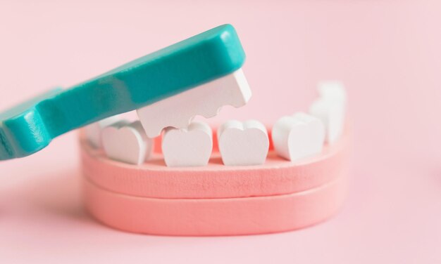 Dental background with wooden toy jaw teeth and toothbrush on a pink background Dentistry dentist clinic concept