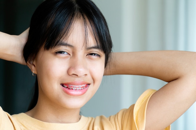 笑顔でカメラを見ている歯列矯正器の女の子、彼女は幸せを感じ、歯科医との良い態度を持っています。彼らが歯科医院に行かなければならないとき、恐れない子供たちをやる気にさせてください。