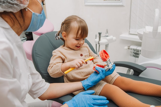 치과 치료. 의치에 양치질하는 방법을 배우는 작은 환자와 치과 의사.
