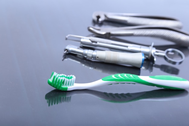 Dental care toothbrush with dentist tools on mirror background.