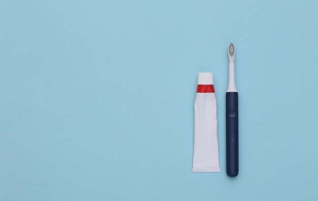 Dental care. Tube of toothpaste with toothbrush on blue background. Copy space