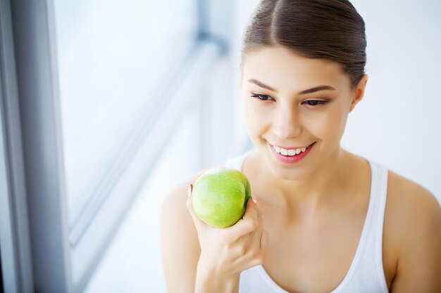 Dental care. Woman With Green Apple at home