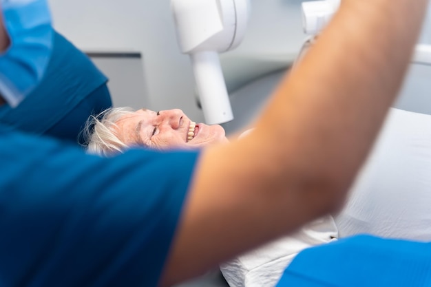 Foto clinica dentale donna anziana seduta sorridente al dentista in attesa del controllo della protesi